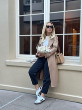 A blonde lady wears a worsted wool trench coat